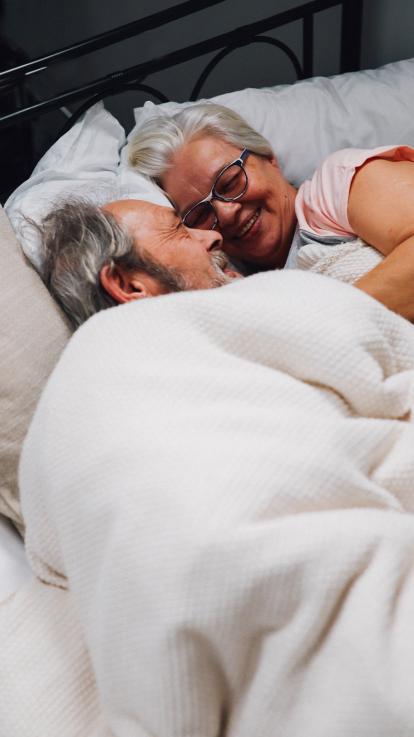 Twee verliefde ouderen in bed. 