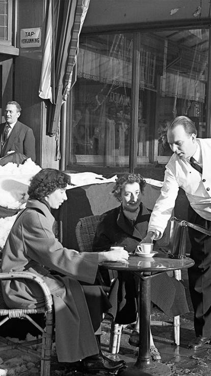 Paar mannen zitten op een terras in de winter terwijl het sneeuwt. 