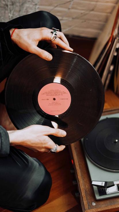 Twee vrienden zitten op bed naar platen te luisteren.