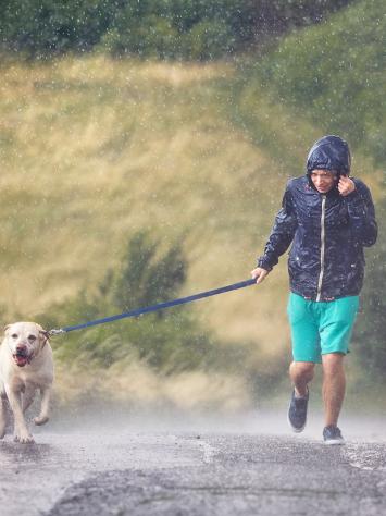 iemand rent met z'n hond in de regen