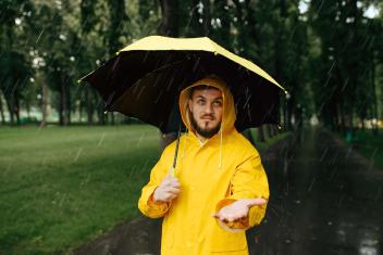 iemand staat met regenjas en paraplu in de regen