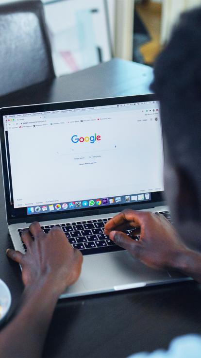 Een man zit achter de computer, iets op te zoeken op Google. Een zoekmachine. 