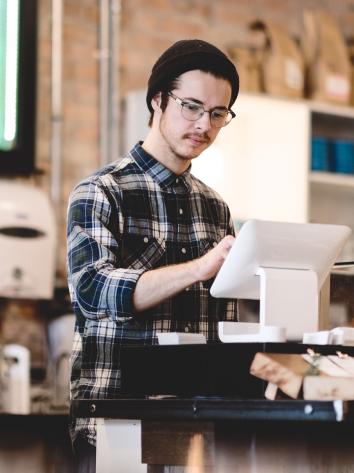 een medewerker van een koffiebar achter de kassa