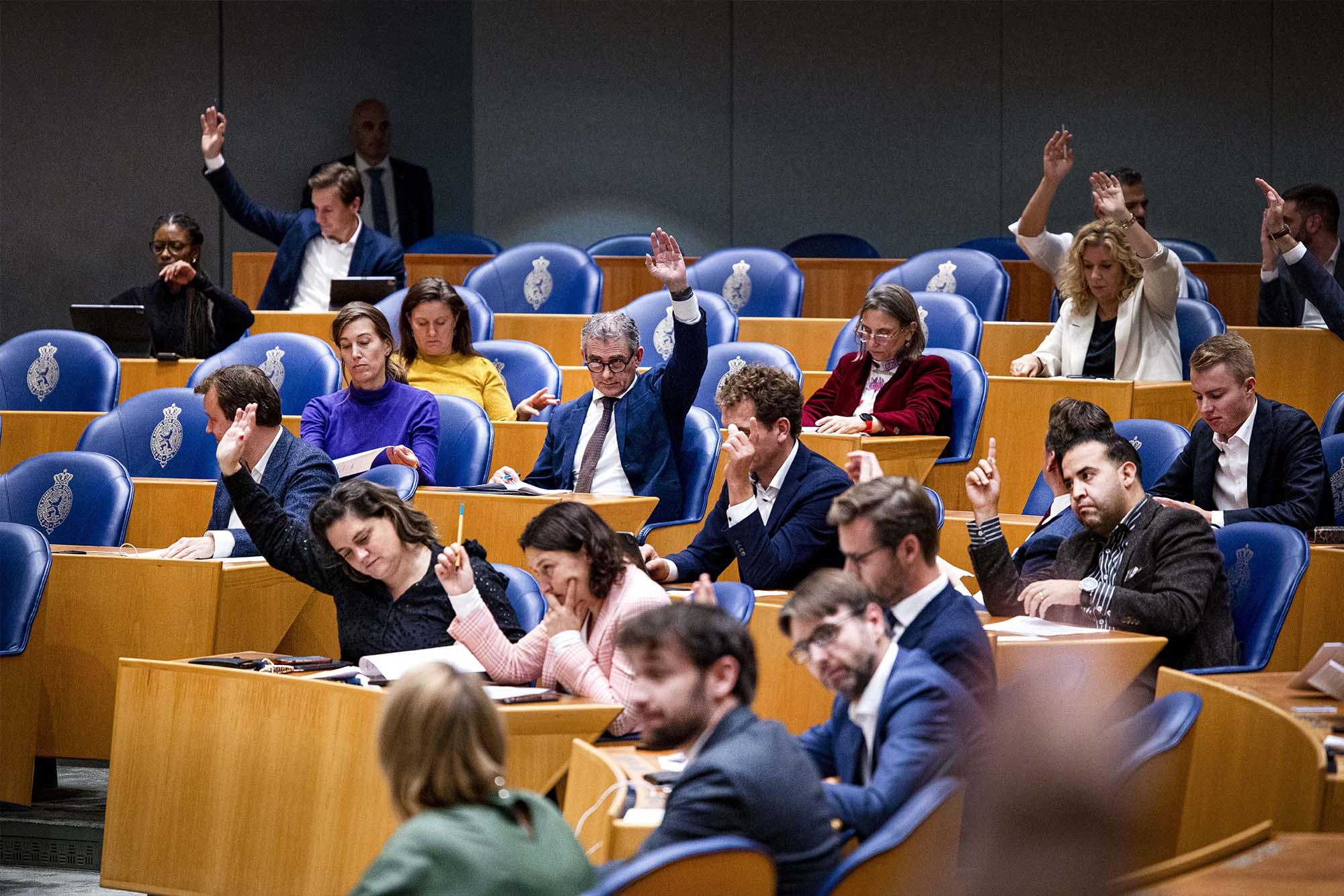 Tweede Kamerleden steken hun hand op tijdens stemmen