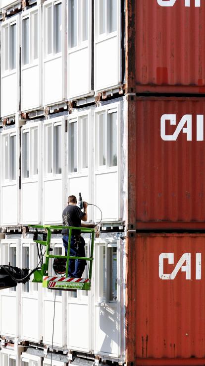 Bouwvakker werkt aan containerwoningen bestemd voor studenten. 