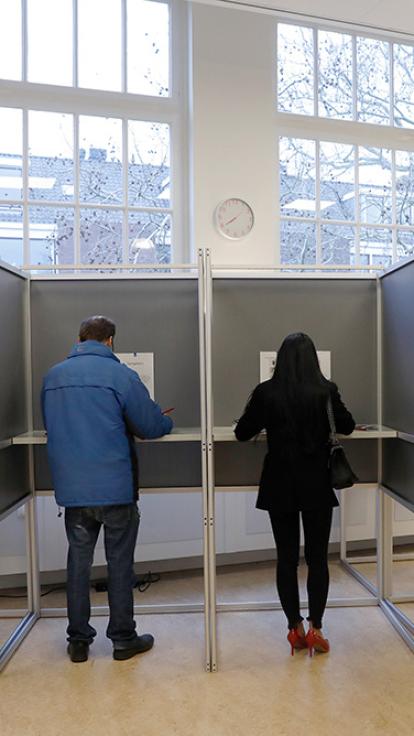 twee mensen staan in stemhokjes