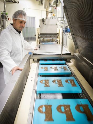 chocoladeletter P in doosjes over een loopband in een fabriek