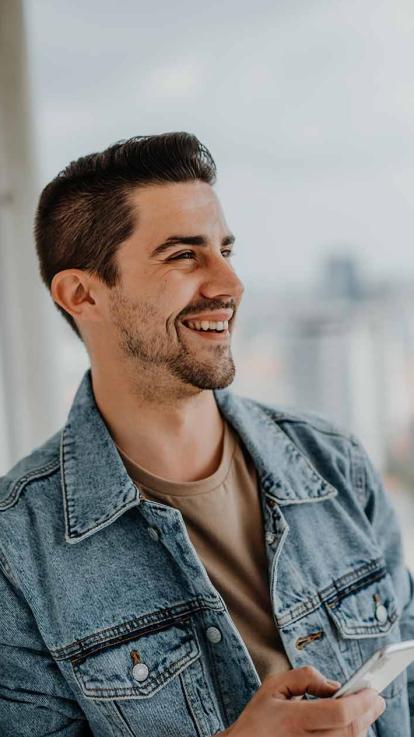 Man lacht en heeft mobiel in hand.