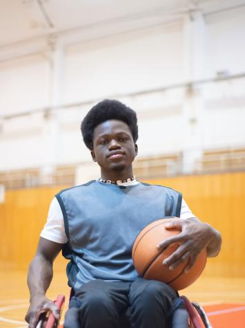 Man in rolstoel met basketbal op schoot