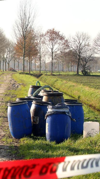 Drugsvaten staan in de greppel van een weiland met politielint 