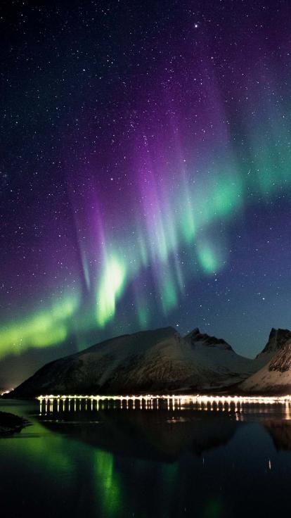 het noorderlicht met paarse en groene kleuren boven een skyline