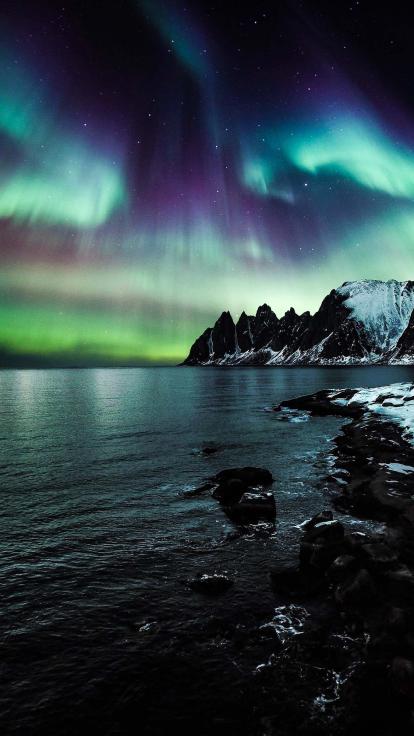 het noorderlicht boven water en besneeuwd gebergte
