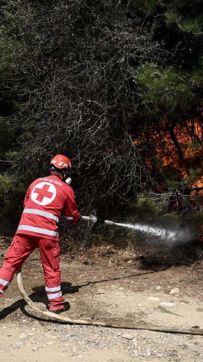 een Rode Kruis-medewerker blust een bosbrand