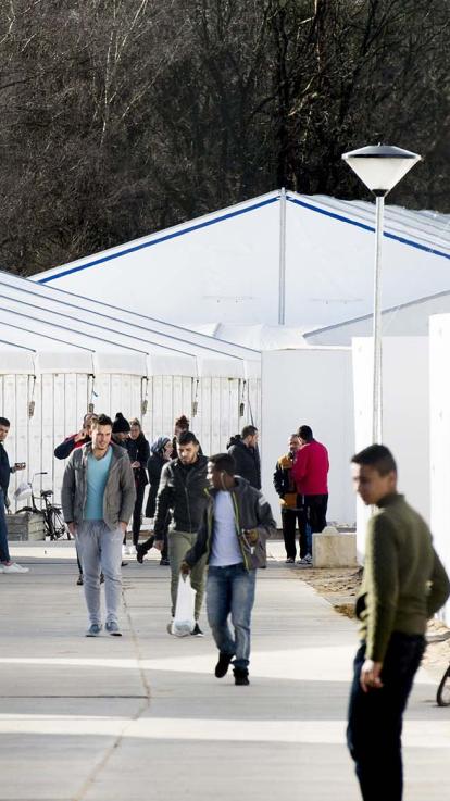 Bewoners van azc Heumensoord lopen over paden van het tentenkamp.