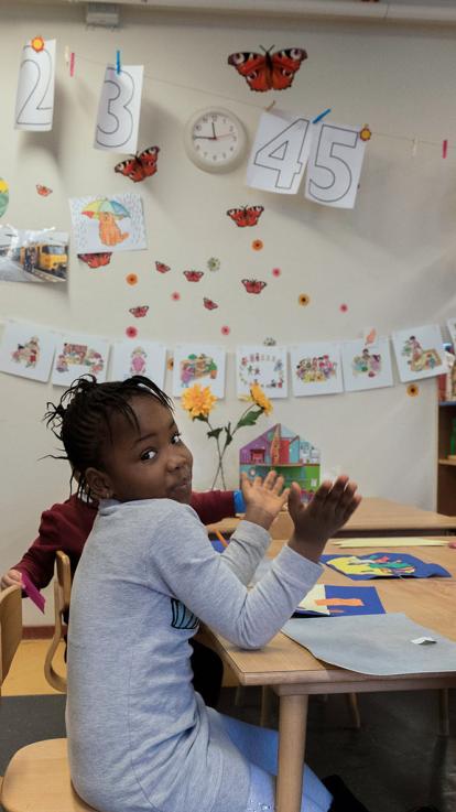 Een kindje aan een schooltafel bezig met een werkje maken.