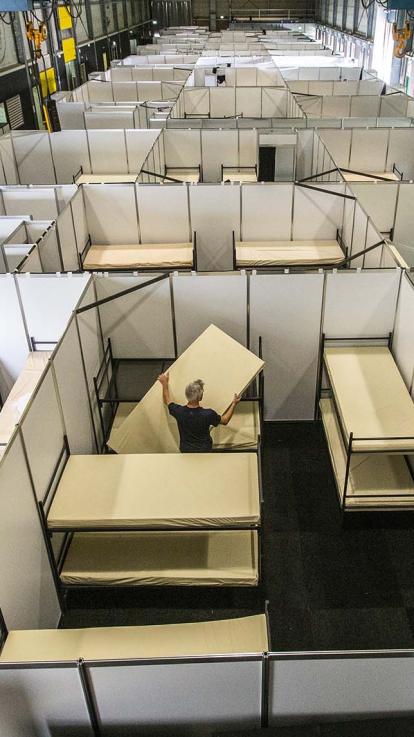 Een gezin zit op bed in hun slaapkamer in het azc.