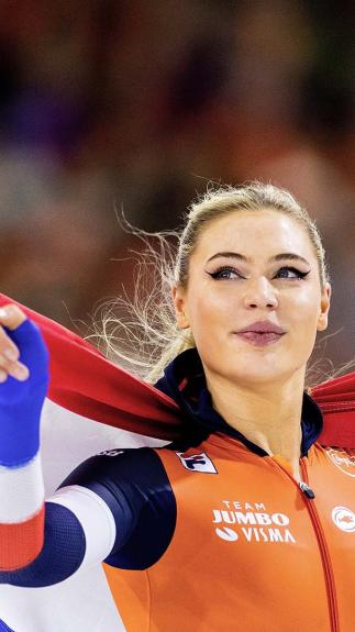Schaatsster Jutta Leerdam met Nederlandse vlag op haar rug.
