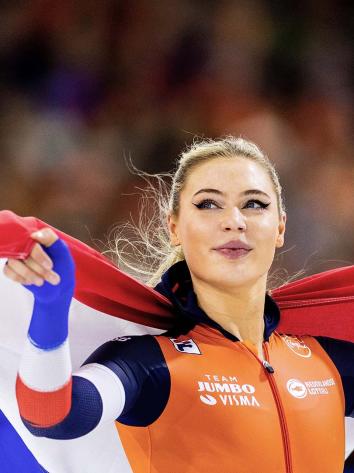 Schaatsster Jutta Leerdam met Nederlandse vlag op haar rug.