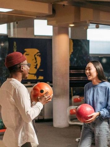 Een groep jongvolwassenen hebben plezier tijdens bowlen.
