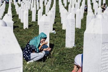 een vrouw in tranen bij een graf van de genocide in Srebrenica