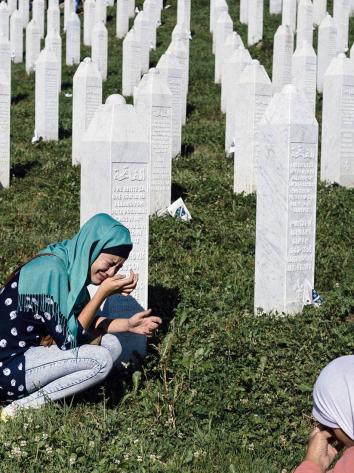 een vrouw in tranen bij een graf van de genocide in Srebrenica