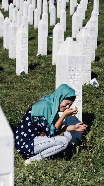 een vrouw in tranen bij een graf van de genocide in Srebrenica