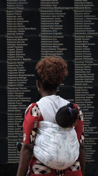 een vrouw kijkt naar een lijst met slachtoffers van de genocide in Rwanda