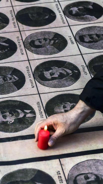 iemand plaatst een kaarsje bij foto's van slachtoffers van de Armeense genocide