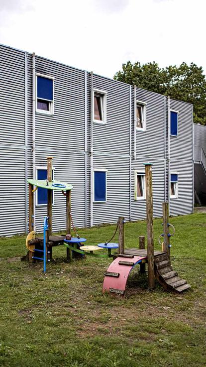 Buitenkant van een azc met een klein speeltuintje ervoor.