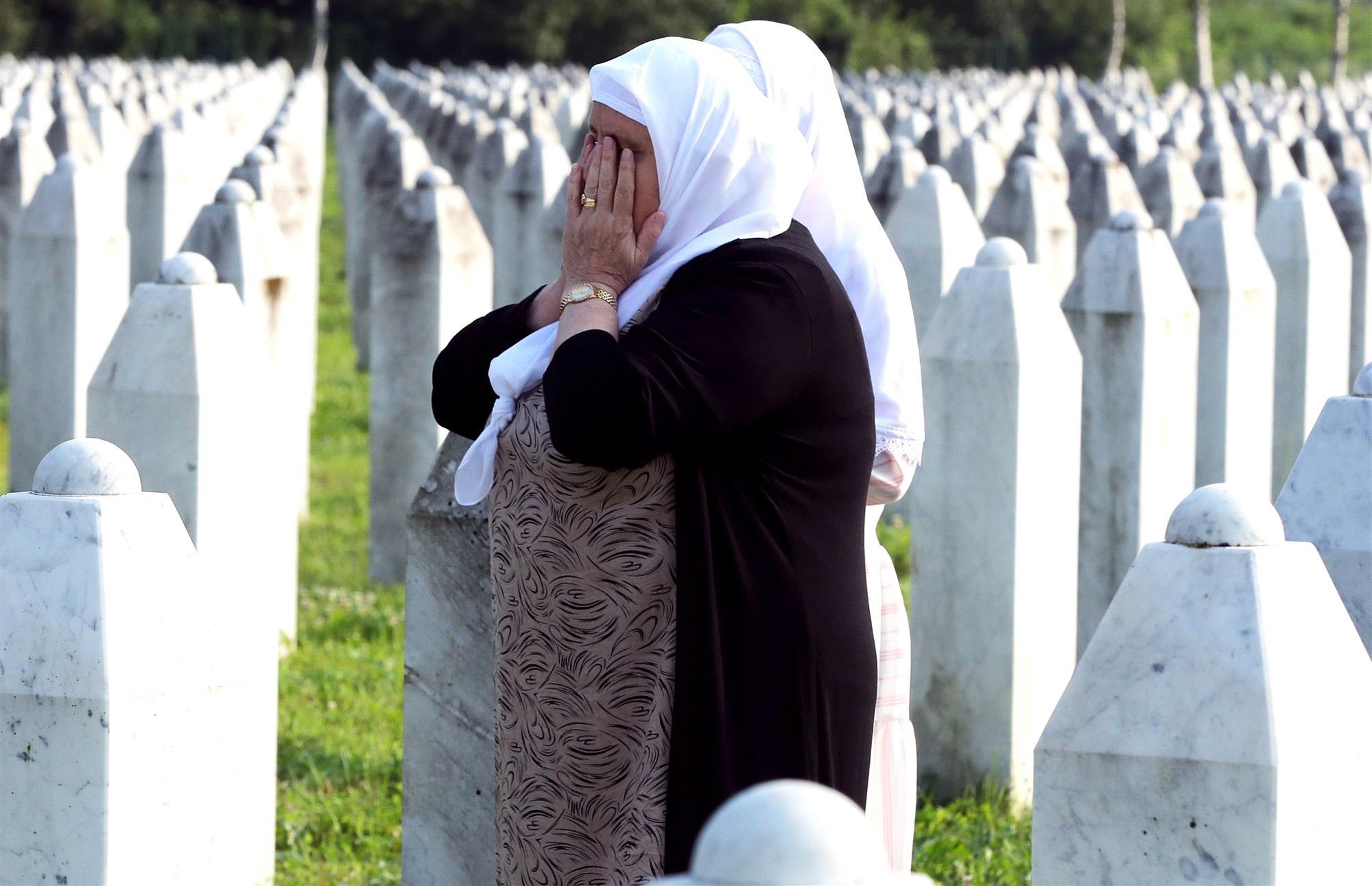 een huilende vrouw bij rijen graven van de genocide in Srebrenica