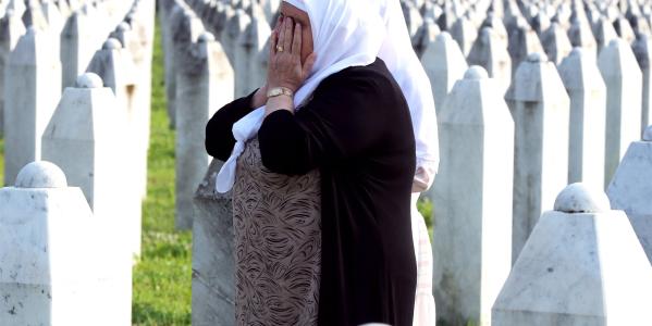 een huilende vrouw bij rijen graven van de genocide in Srebrenica
