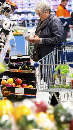 Een mevrouw pakt champignons in de supermarkt