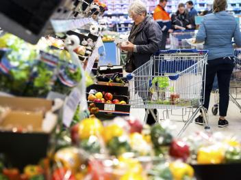 Een mevrouw pakt champignons in de supermarkt