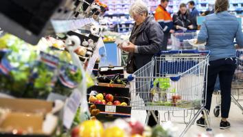Een mevrouw pakt champignons in de supermarkt