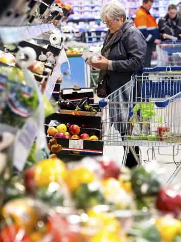 Een mevrouw pakt champignons in de supermarkt