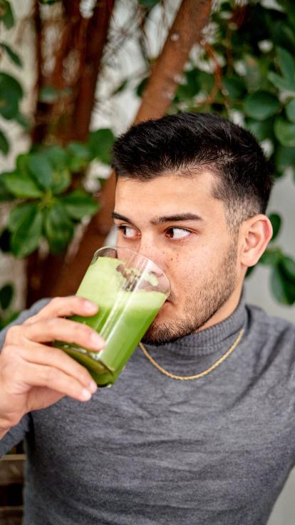 een persoon drinkt een groene smoothie