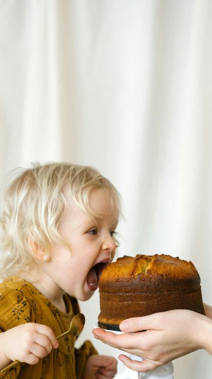 een kind opent haar mond voor taart