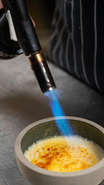 iemand verhit de suiker met een brander voor de crème brûlée 