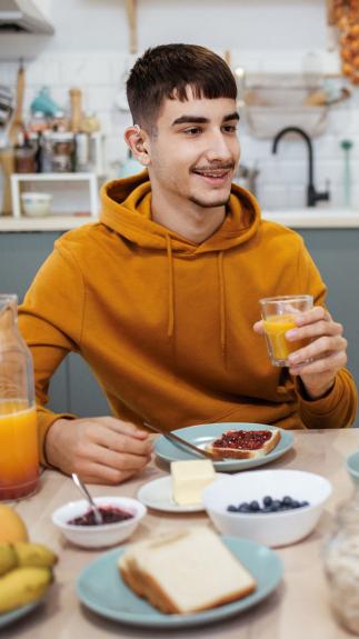 iemand is aan het ontbijten met melk en een witte boterham met jam