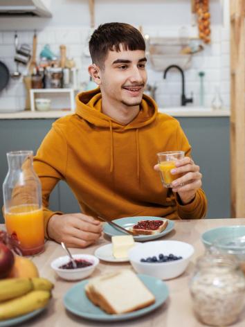 iemand is aan het ontbijten met melk en een witte boterham met jam