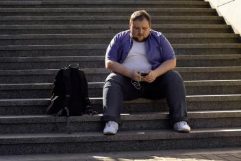 een man met obesitas zit op een trap naar muziek te luisteren