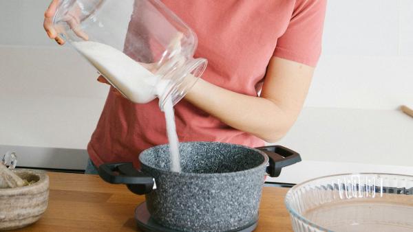 een vrouw doet suiker in een pan