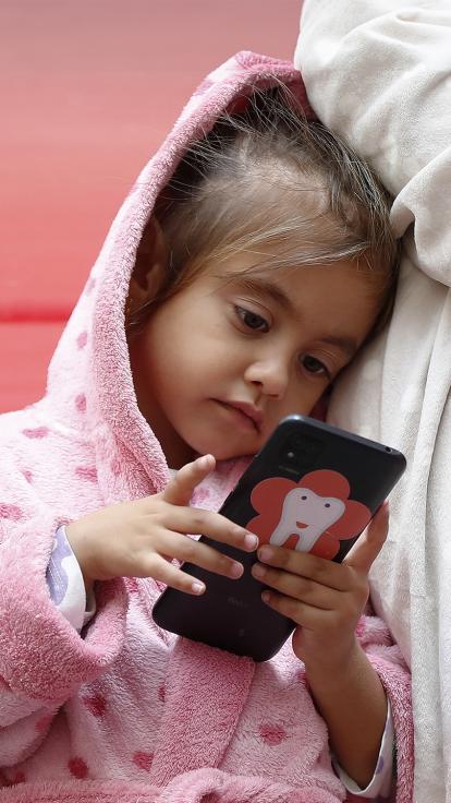 Meisje in roze badjas kijkt naar een smartphone en leunt op schouder