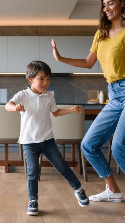 Moeder en zoon dansen samen in woonkamer en kijken naar laptop