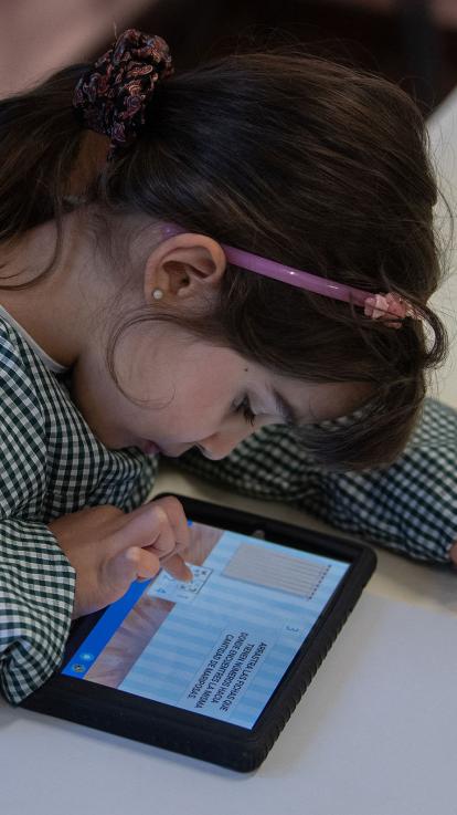 Meisje zit gebogen over een tablet met tekst 