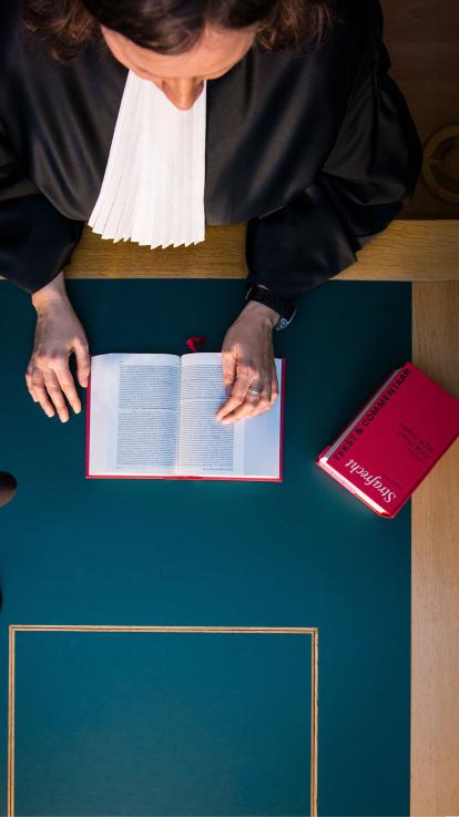 Een rechter bladert in toga door het wetboek van strafrecht