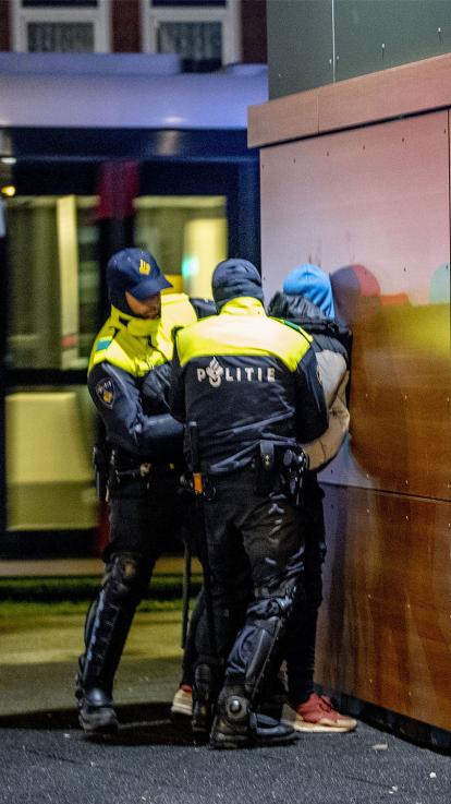 Twee politie agenten arresteren een man op straat en doen handboeien bij hem om