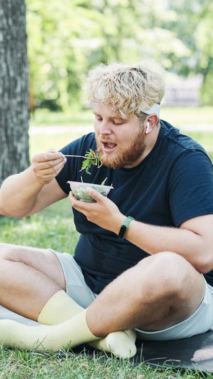 een sporter eet een salade in het park
