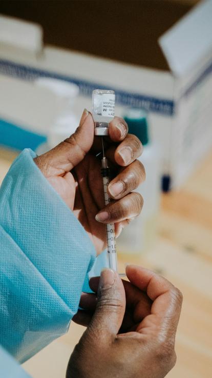 een vaccin wordt uit een flacon gehaald door een arts 