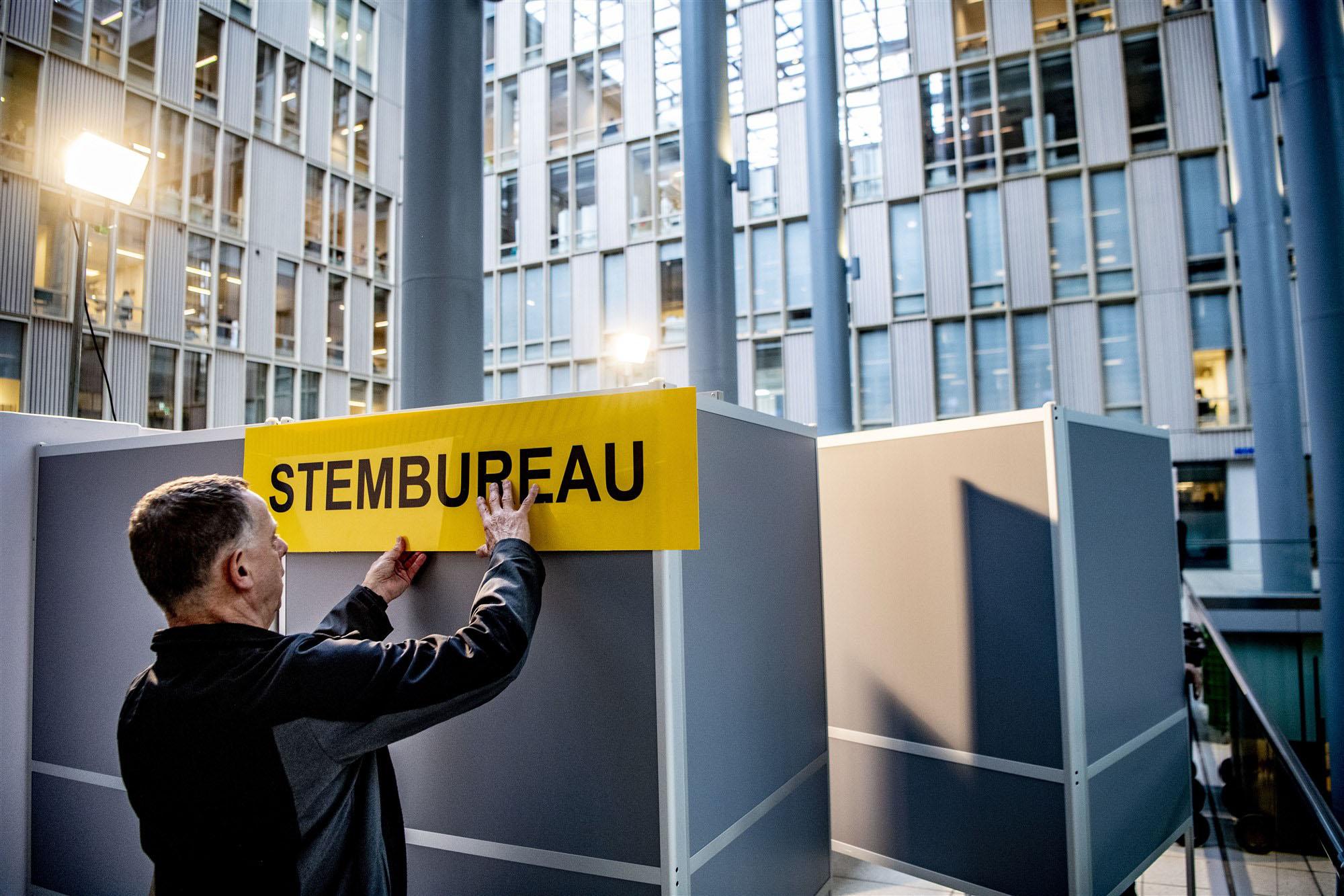iemand hangt een bordje voor een stembureau op